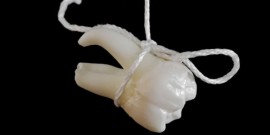 Tooth extracting method. Real human tooth hanging on thread